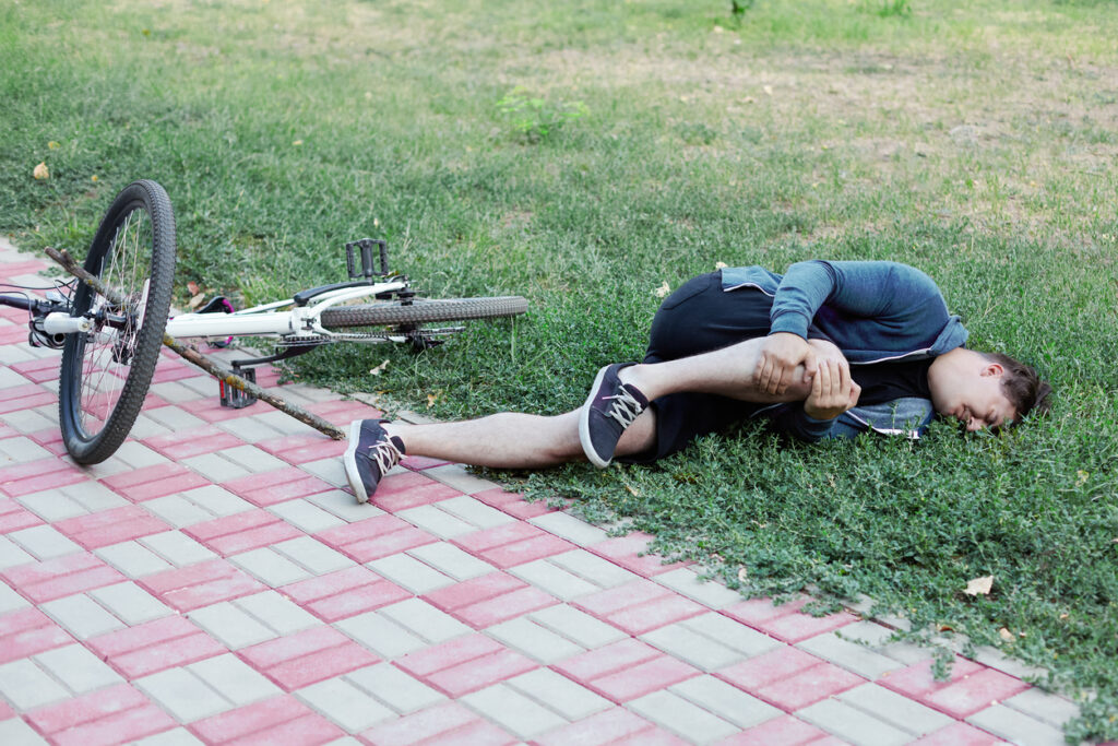 Injured cyclist lying beside fallen bicycle in Irvine, CA
